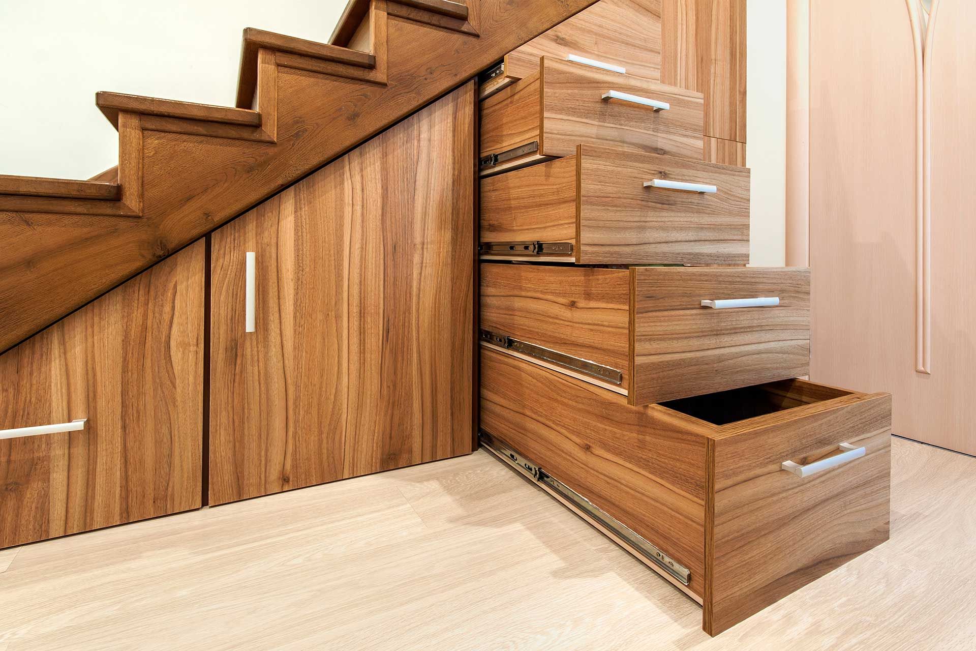 A wooden staircase with drawers underneath it.