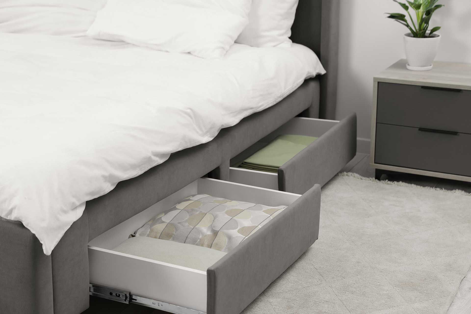 A bedroom with a bed and two drawers underneath it