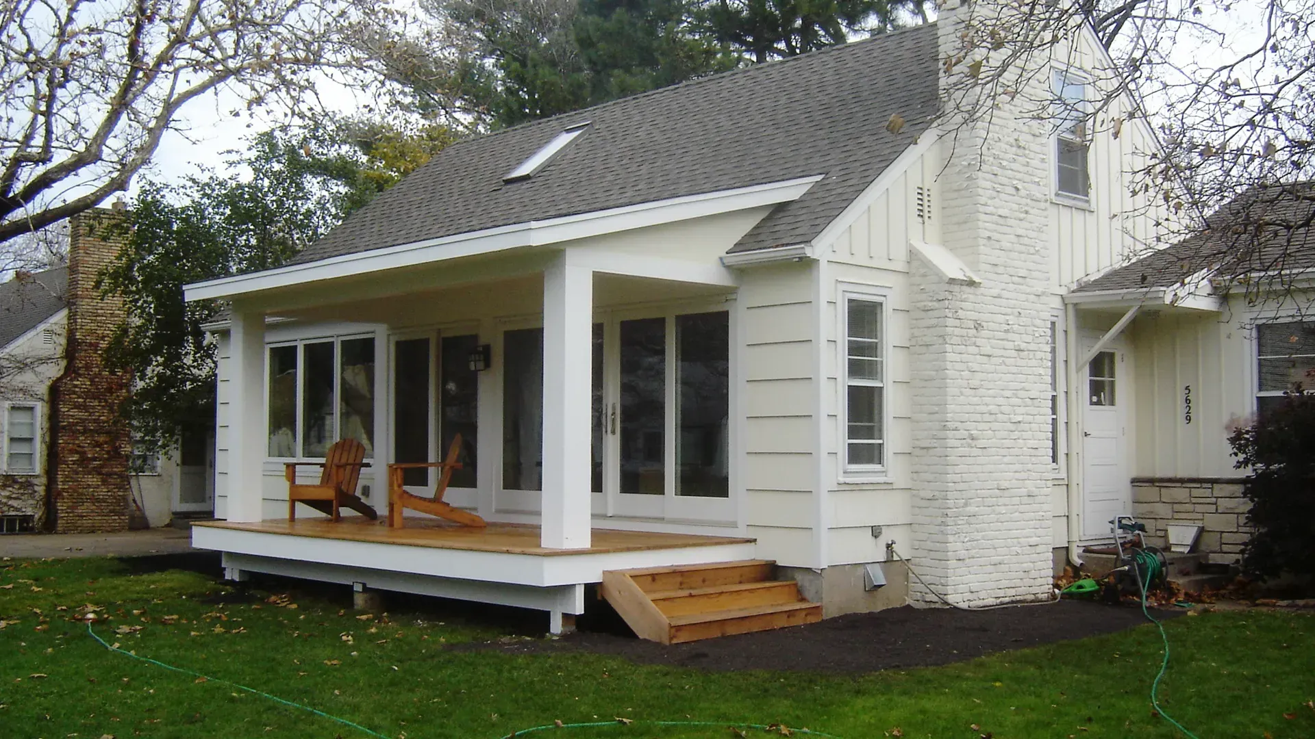 White house with brick chimney and covered front deck porch