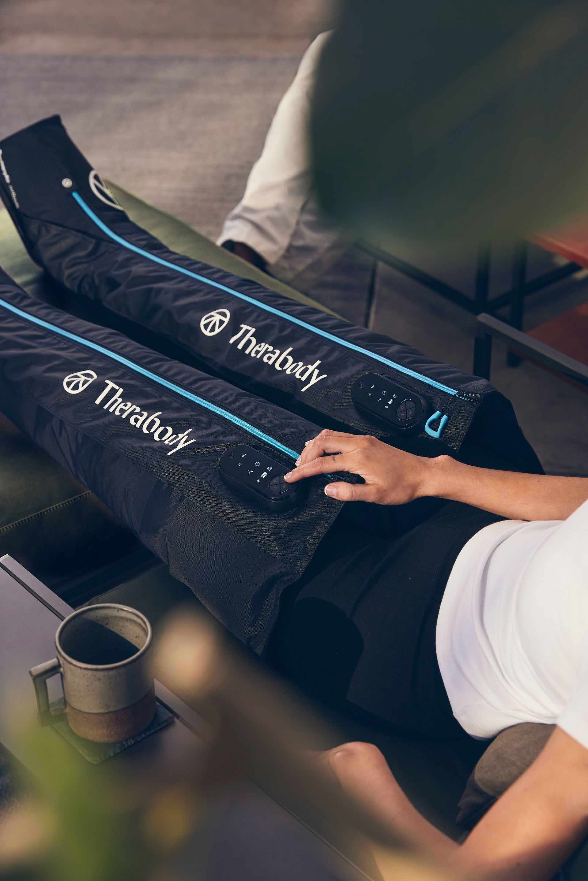 A woman is laying on a couch with a pair of compression socks on her legs.