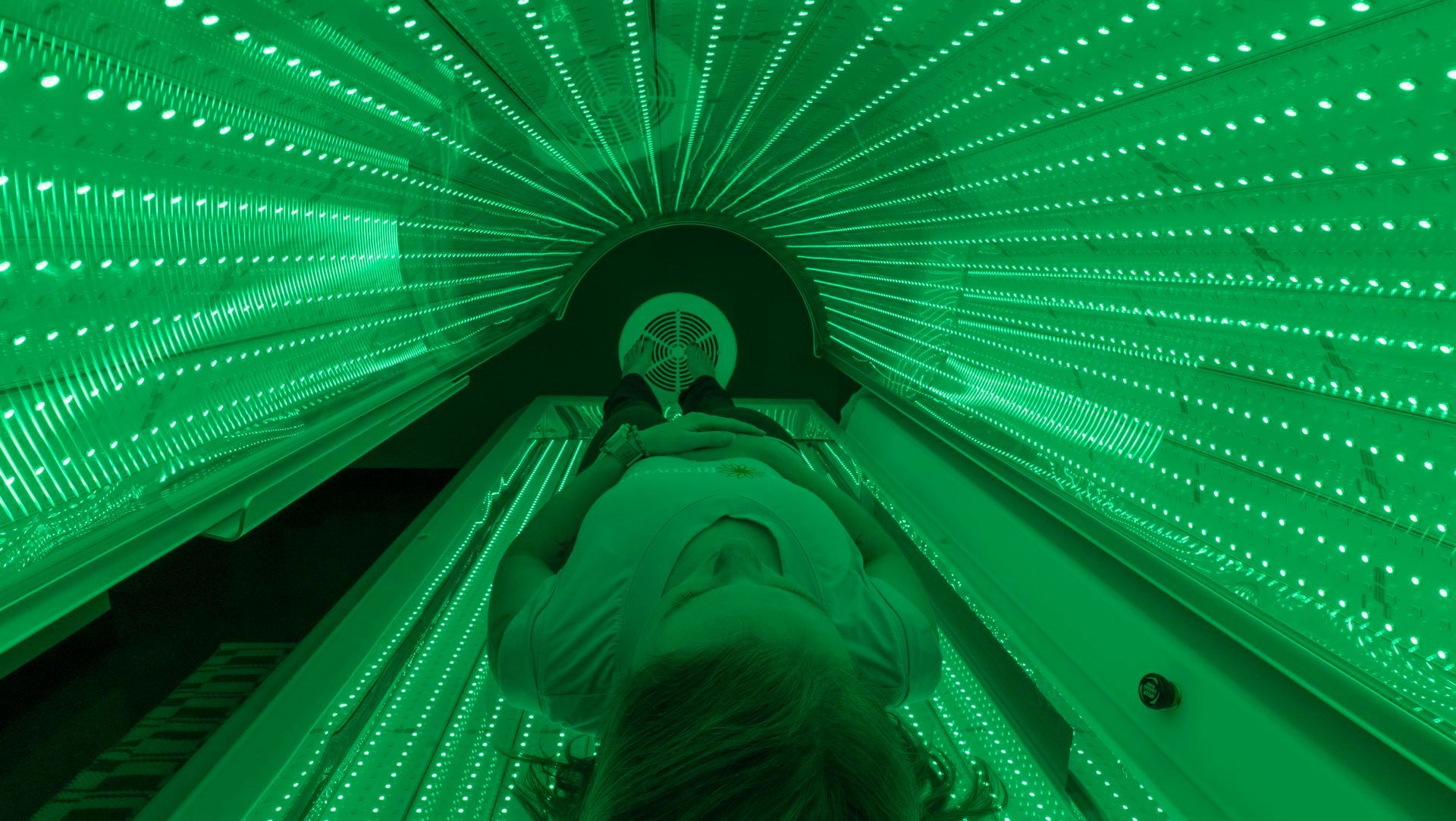 A woman is laying in a tunnel of colorful lights.