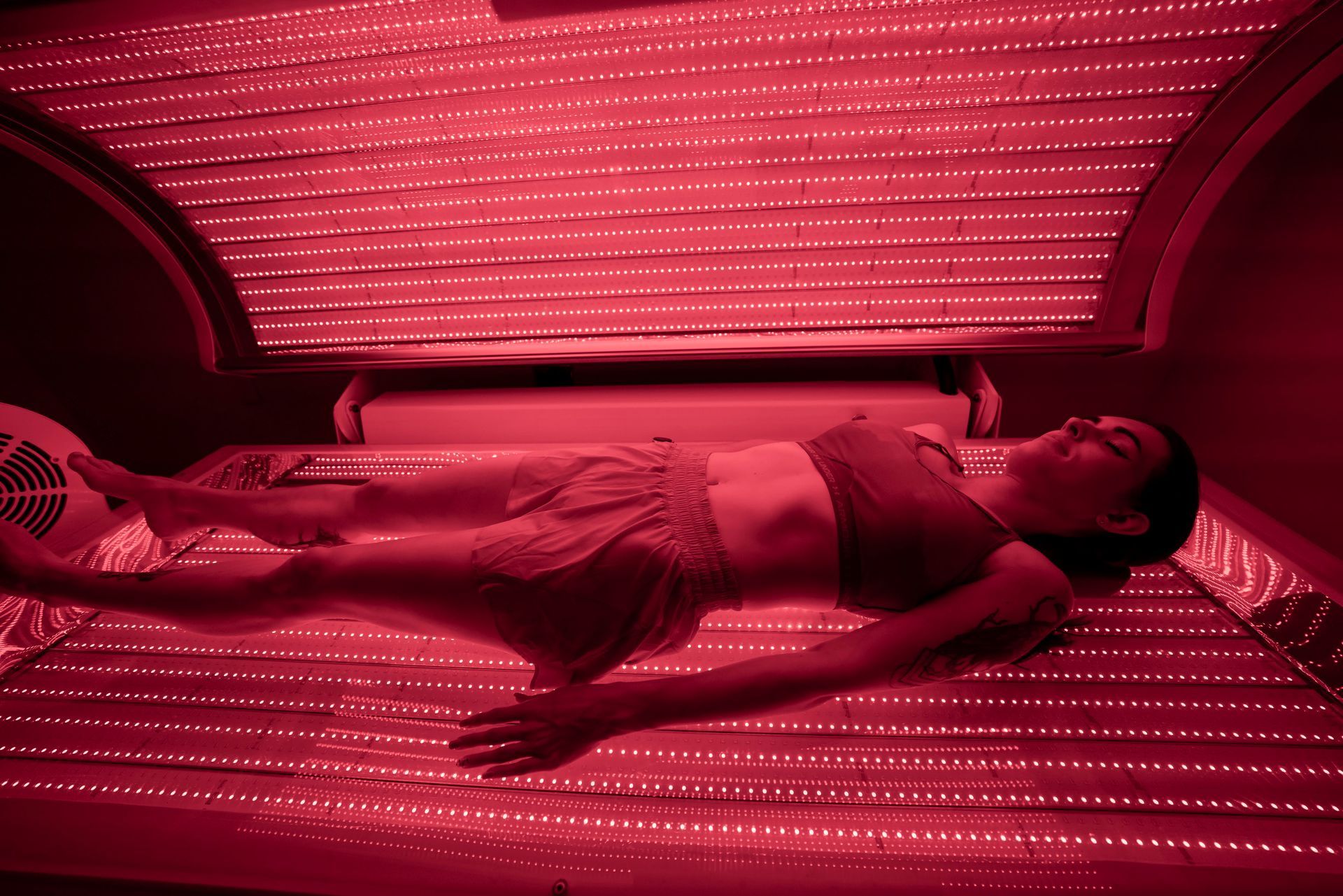 A woman is laying in a bed with red lights on it.
