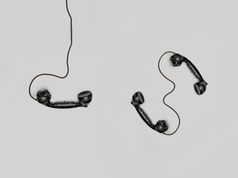 Two old telephones hanging from a wire on a white background