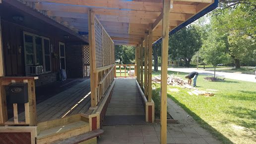 A wooden walkway leading to a house with a covered porch.