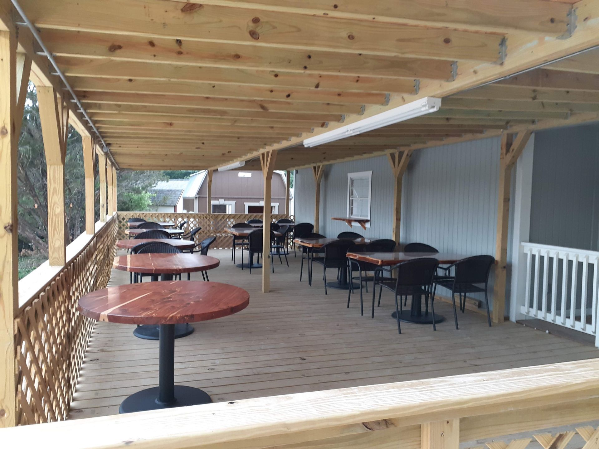 A wooden deck with tables and chairs under a canopy