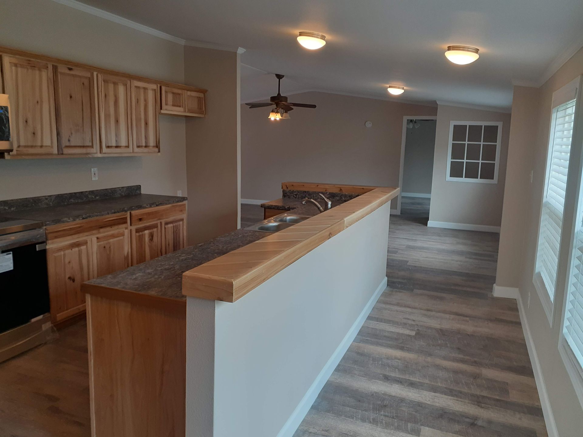 A kitchen in a mobile home with wooden cabinets and a ceiling fan.