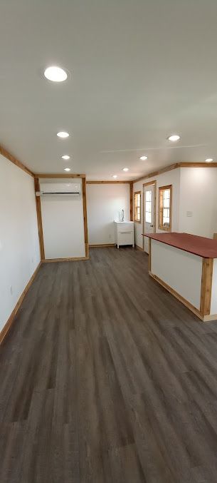 A large empty room with hardwood floors and white walls.