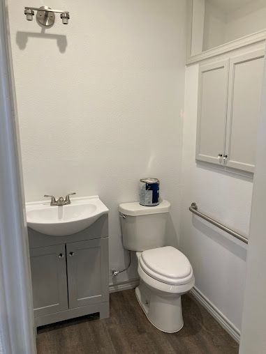 A bathroom with a toilet , sink , and cabinets.