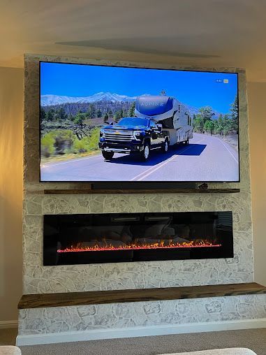 A living room with a fireplace and a flat screen tv on the wall.