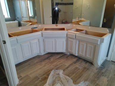 A bathroom with white cabinets and a large mirror.
