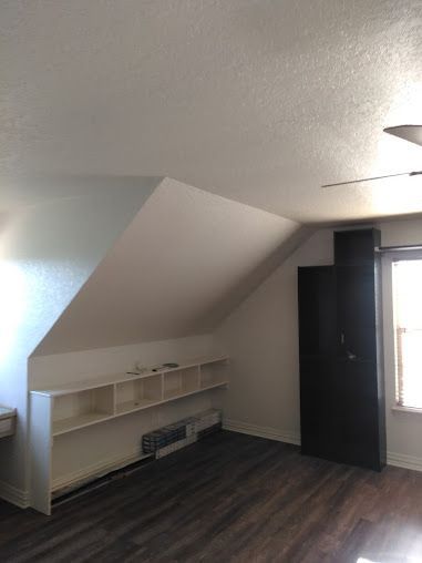 A living room with a slanted ceiling and a shelf.