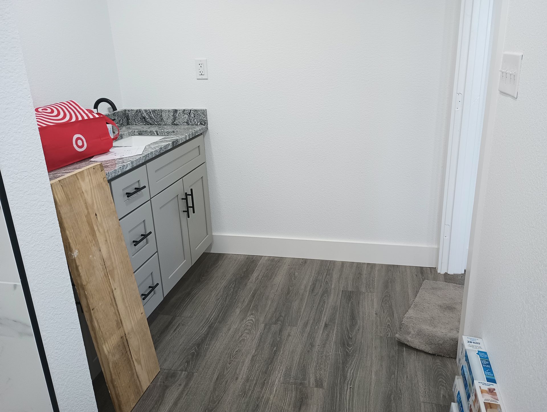 A kitchen with a sink , cabinets , and a wooden floor.