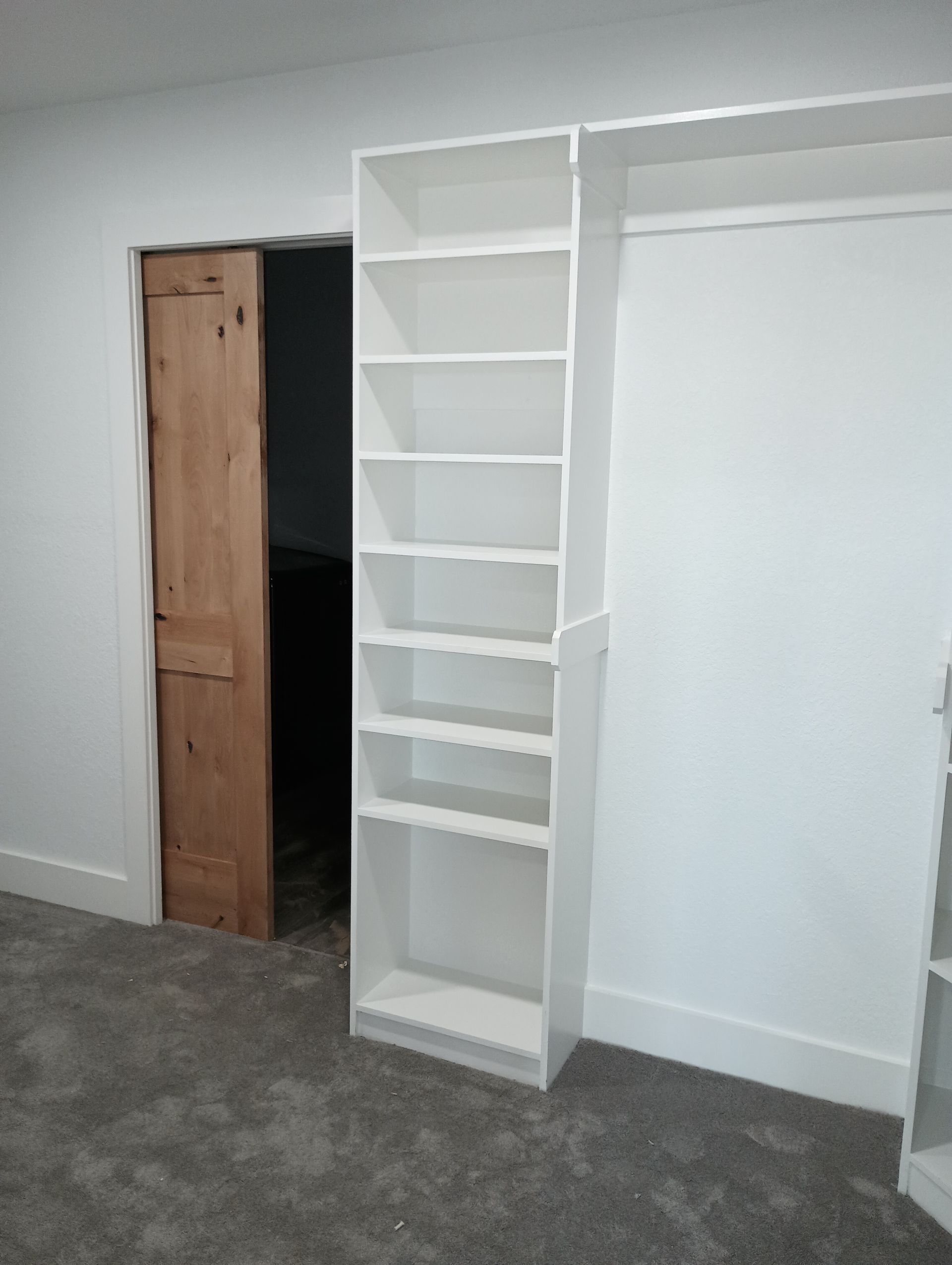 A closet with white shelves and a wooden door