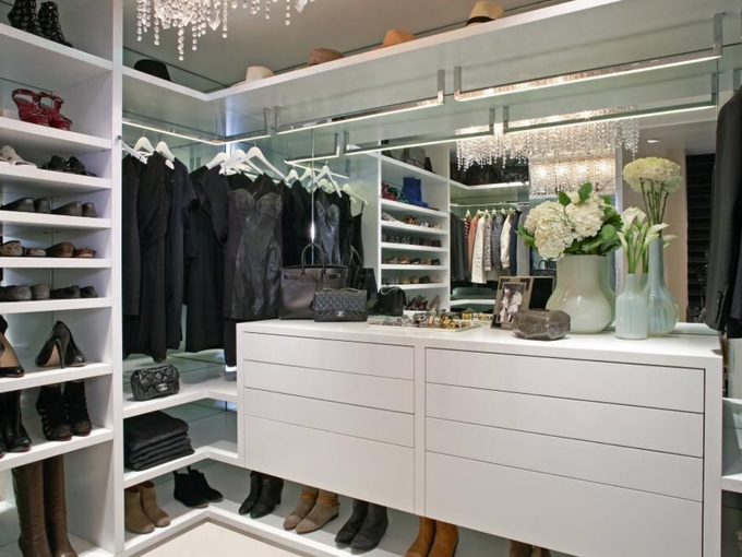 A walk in closet filled with lots of clothes and shoes.