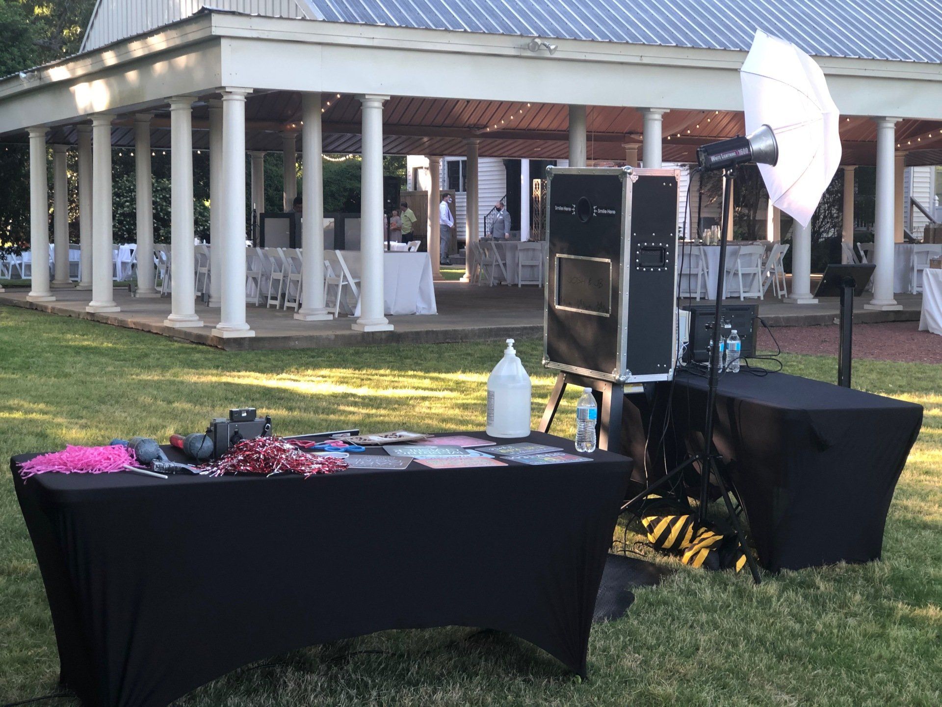 a photo booth is set up in the grass in front of a gazebo .