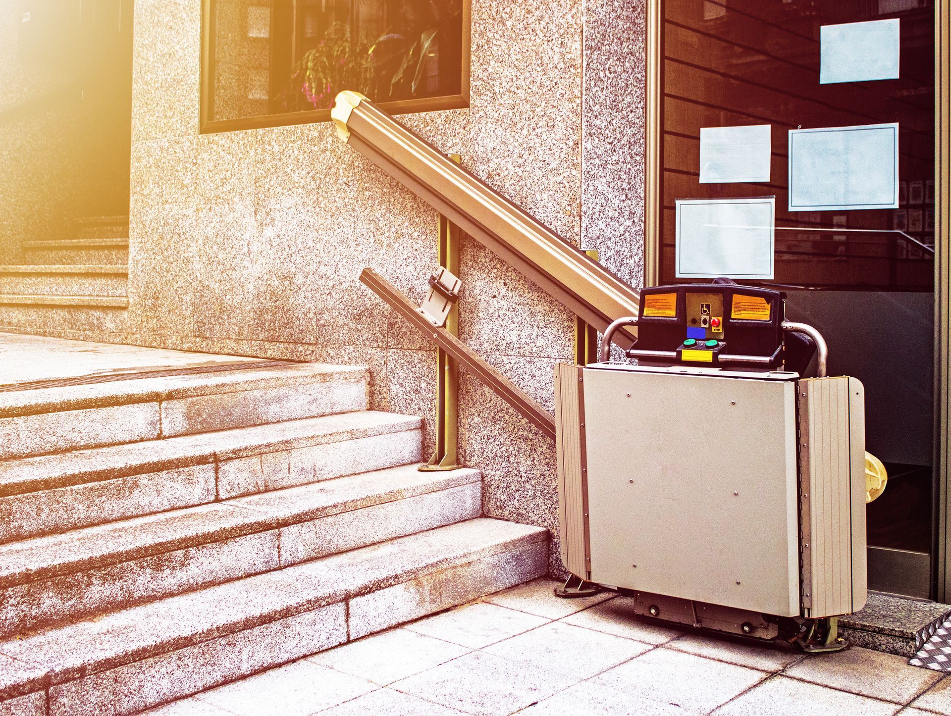 A stair lift sits outside a building next to a set of stairs - San Luis Obispo, CA - Coastal Accessibility