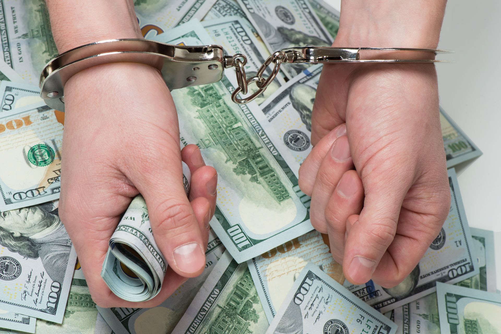 Hands in handcuffs holding money, showcasing criminal charge bail money for release.