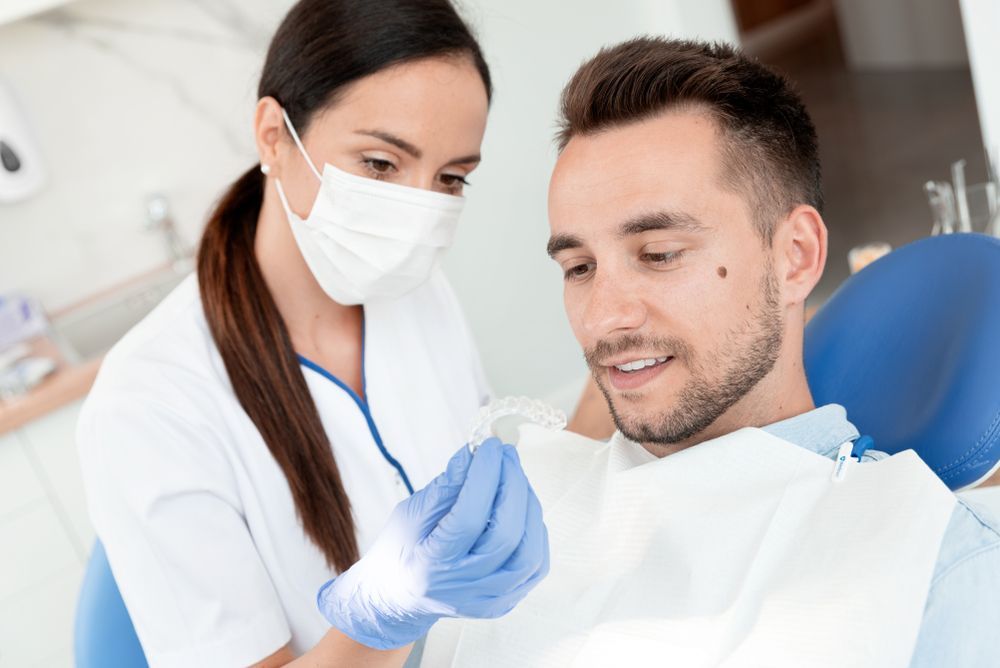 Dentist Showing a Clear Aligner to a Patient in a Dental Office — Tamworth Orthocare In Muswellbrook, NSW