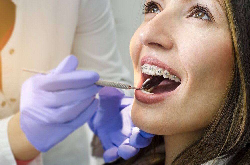 Woman With Braces Having Dental Exam by Dentist in Purple Gloves — Tamworth Orthocare In Tamworth, NSW