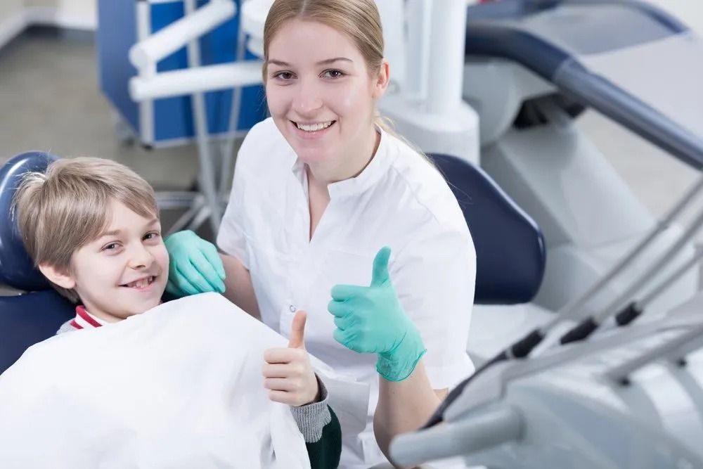 Dentist With a Child Patient Giving Thumbs Up in Dental Chair — Tamworth Orthocare In Muswellbrook, NSW