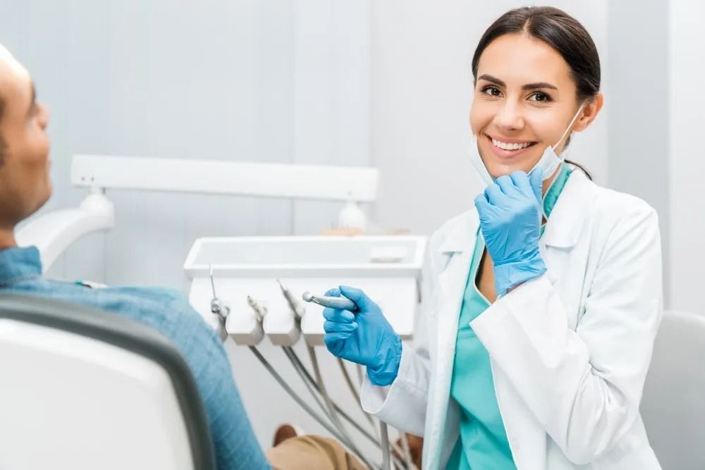 Dentist Smiling, Holding Tool, With Patient in Dental Chair — Tamworth Orthocare In Tamworth, NSW