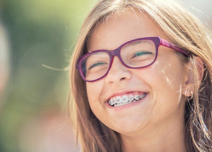 Girl With Eyeglasses and Braces Smiles Broadly Outdoors — Tamworth Orthocare In Scone, NSW