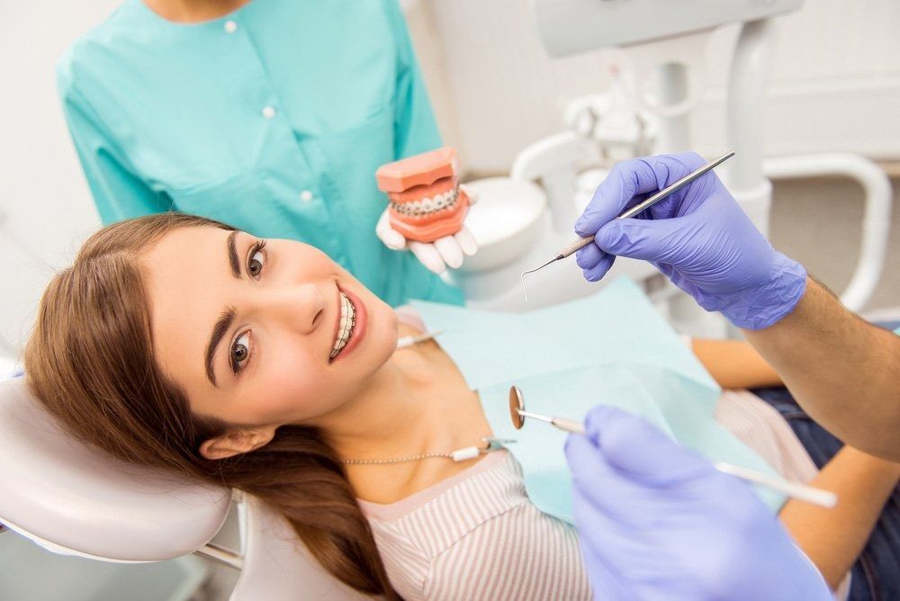 Woman in Dental Chair Smiles While Dentist Works — Tamworth Orthocare In Muswellbrook, NSW