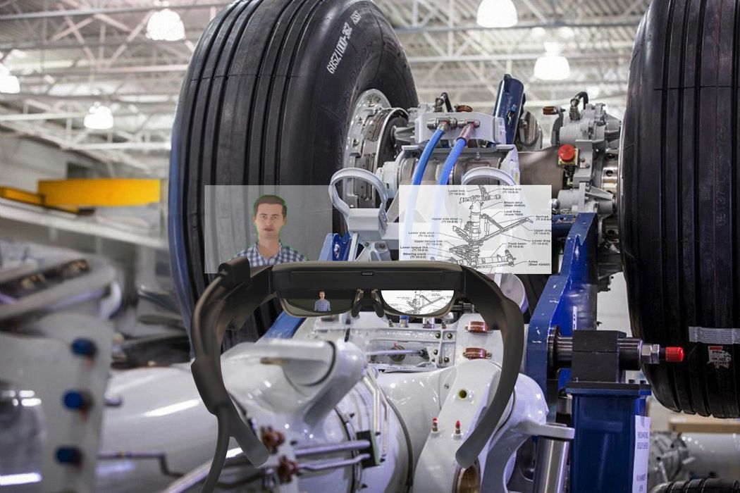 A man is standing in front of a large tire in a factory.