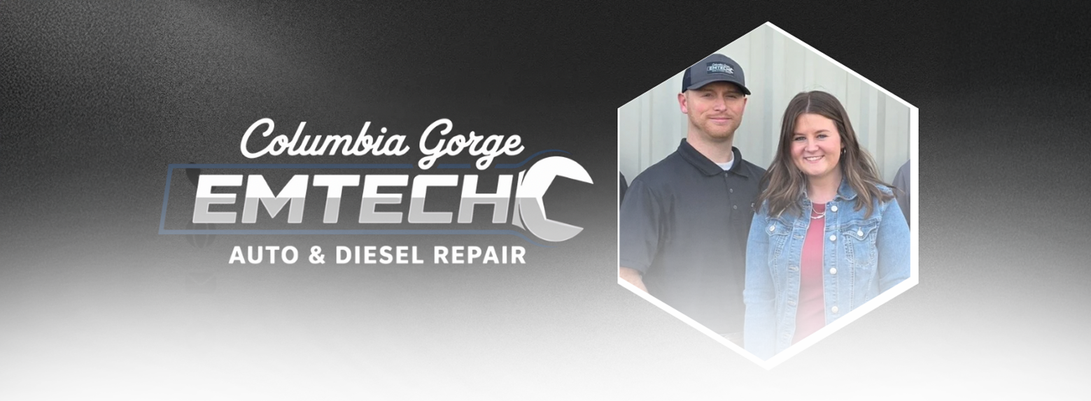 Two mechanics examining a car engine in an auto repair shop. The hood is open.