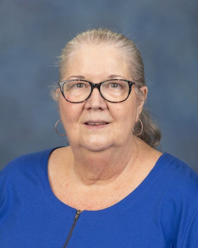 a woman wearing glasses and a blue shirt is posing for a picture .