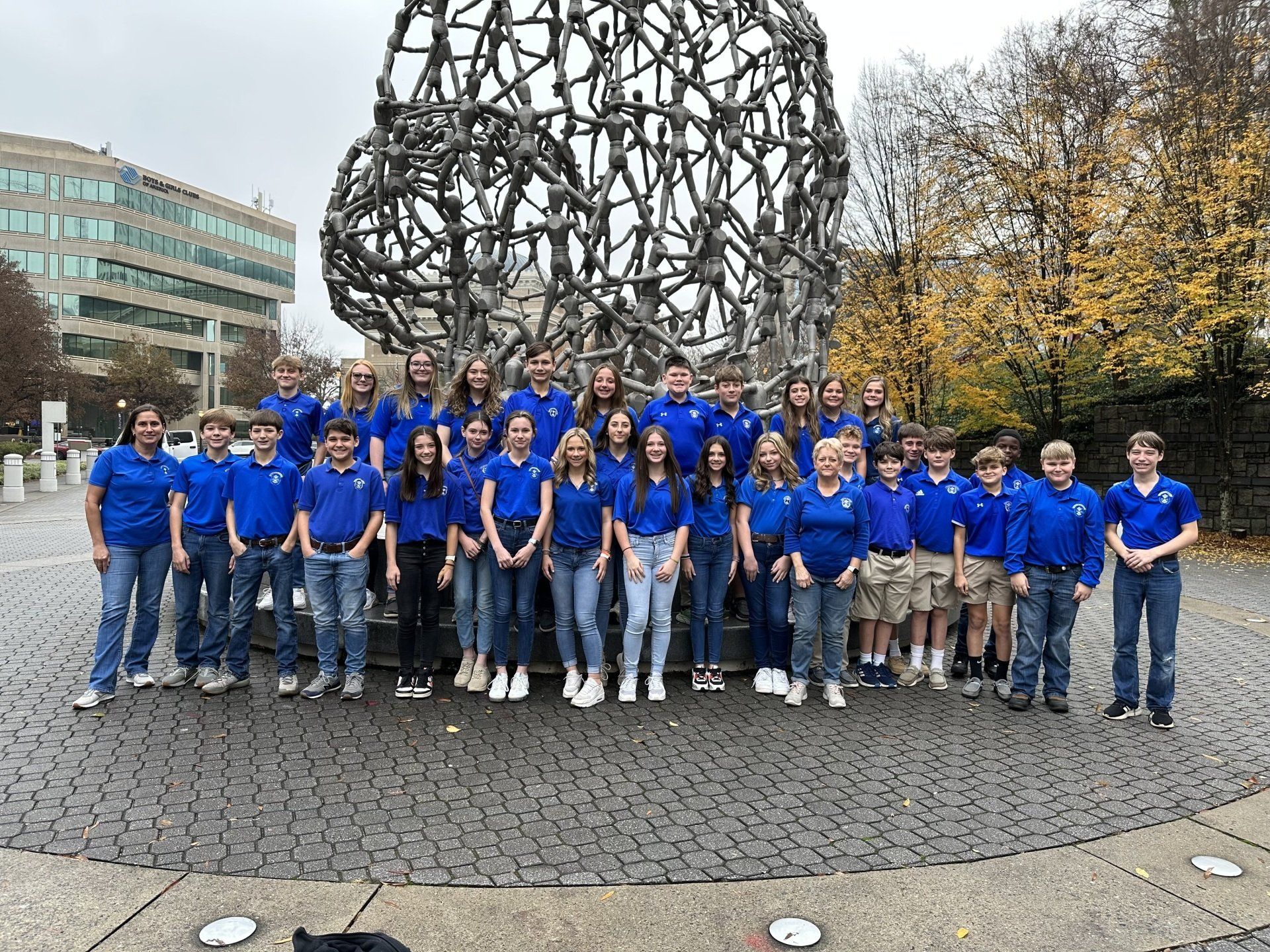 a group of young people are posing for a picture in front of a sculpture .
