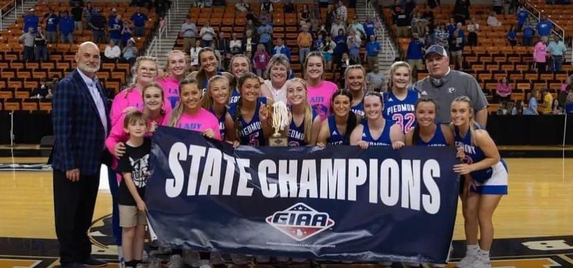 a group of people holding a state champions banner on a basketball court .