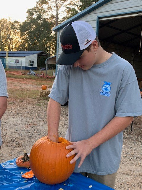 a man in a grey shirt is carving a pumpkin