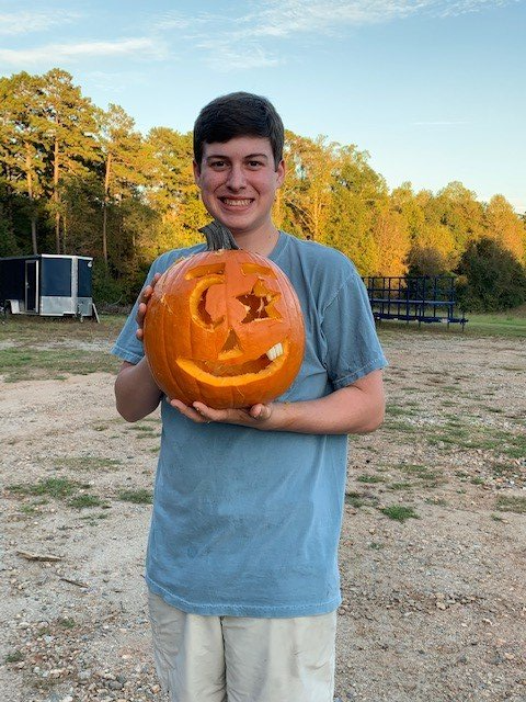 a man in a blue shirt is holding a carved pumpkin