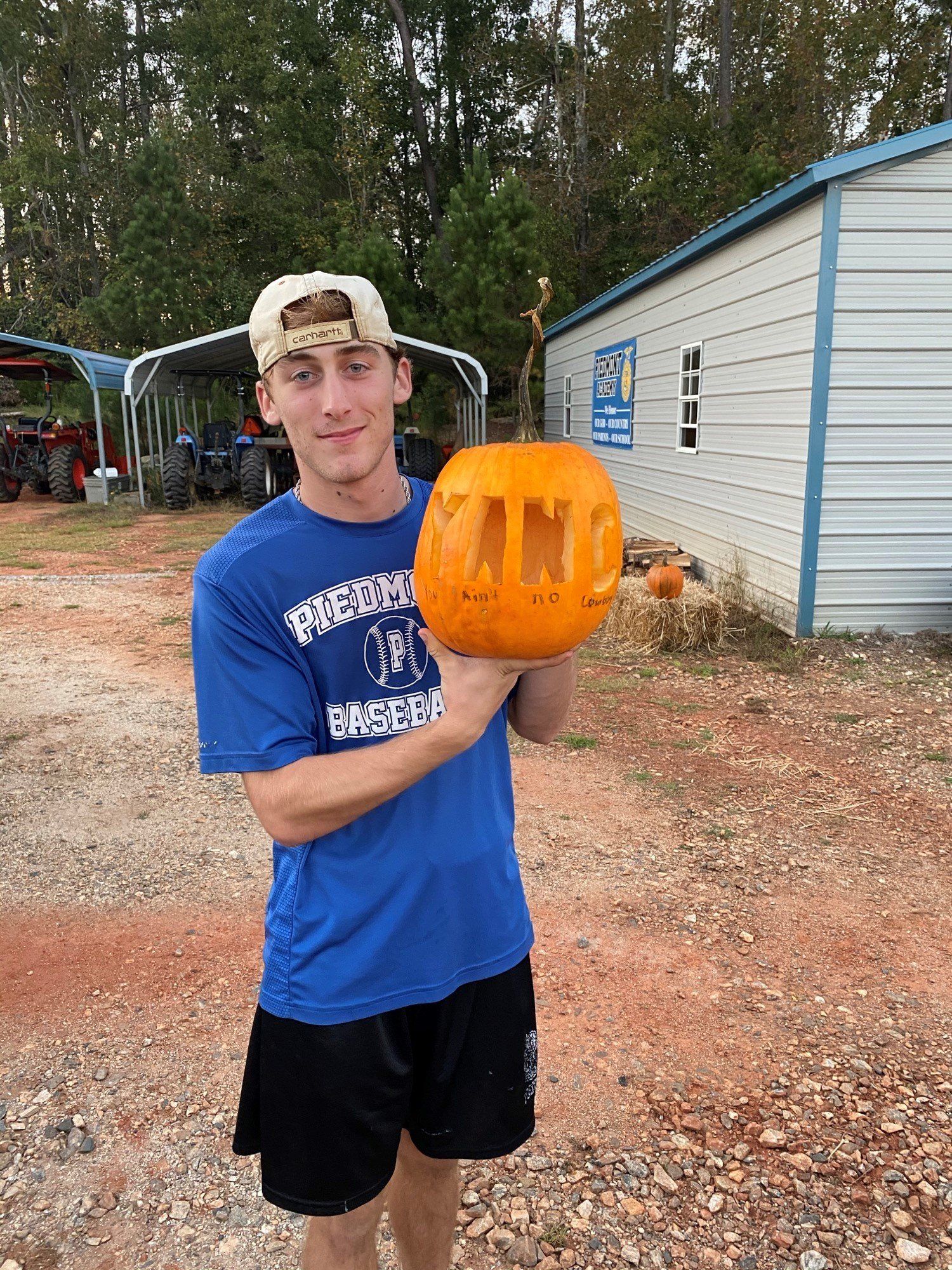 a young man in a blue shirt is holding a carved pumpkin .