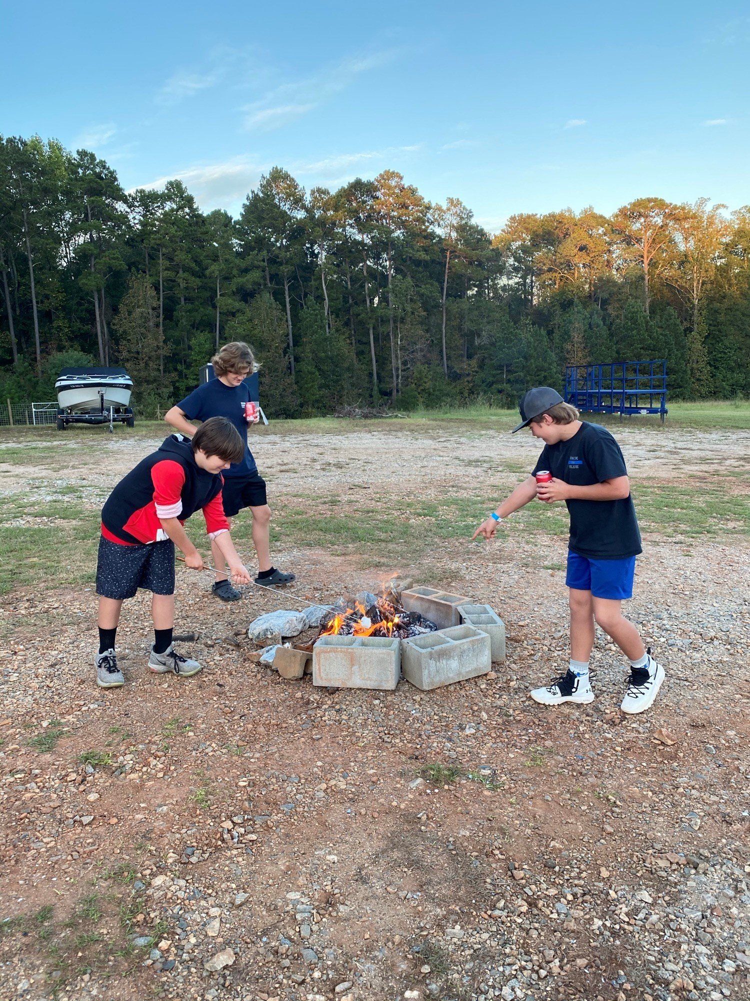 a group of young boys are standing around a fire pit .