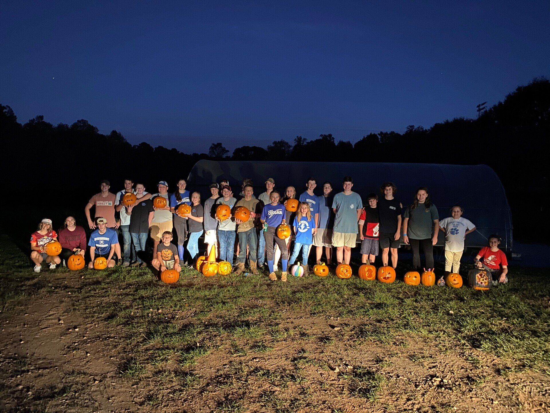 a group of people are posing for a picture in a field of pumpkins .