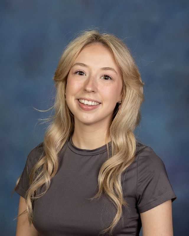 the woman is wearing a black sweater and smiling for the camera .