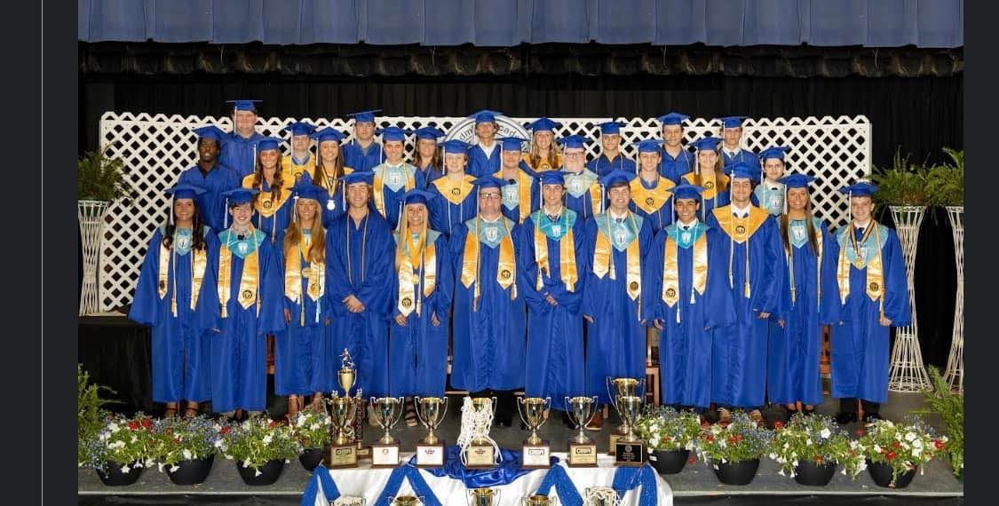 a group of graduates are posing for a picture on a stage .