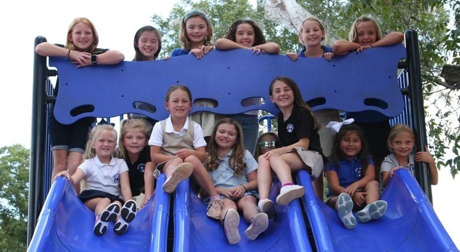 a group of young girls are sitting on a blue slide