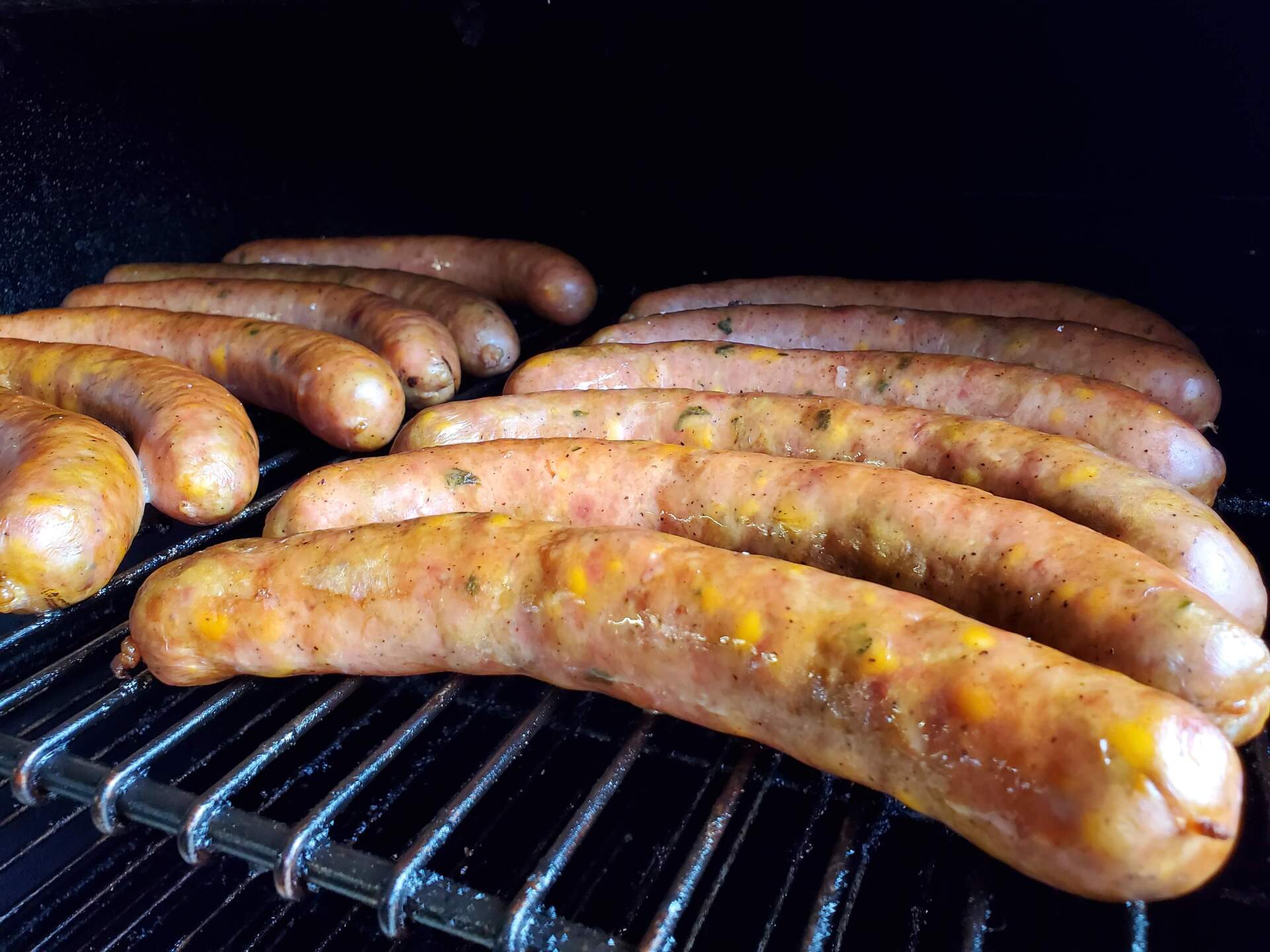 A bunch of sausages are cooking on a grill