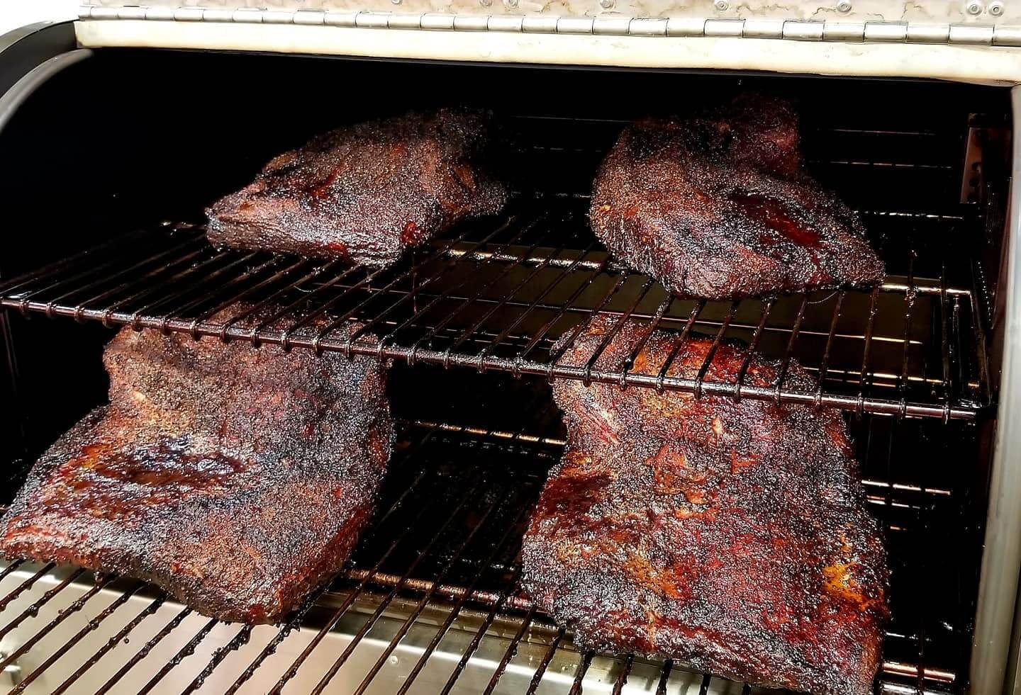 Several pieces of meat are cooking on a grill