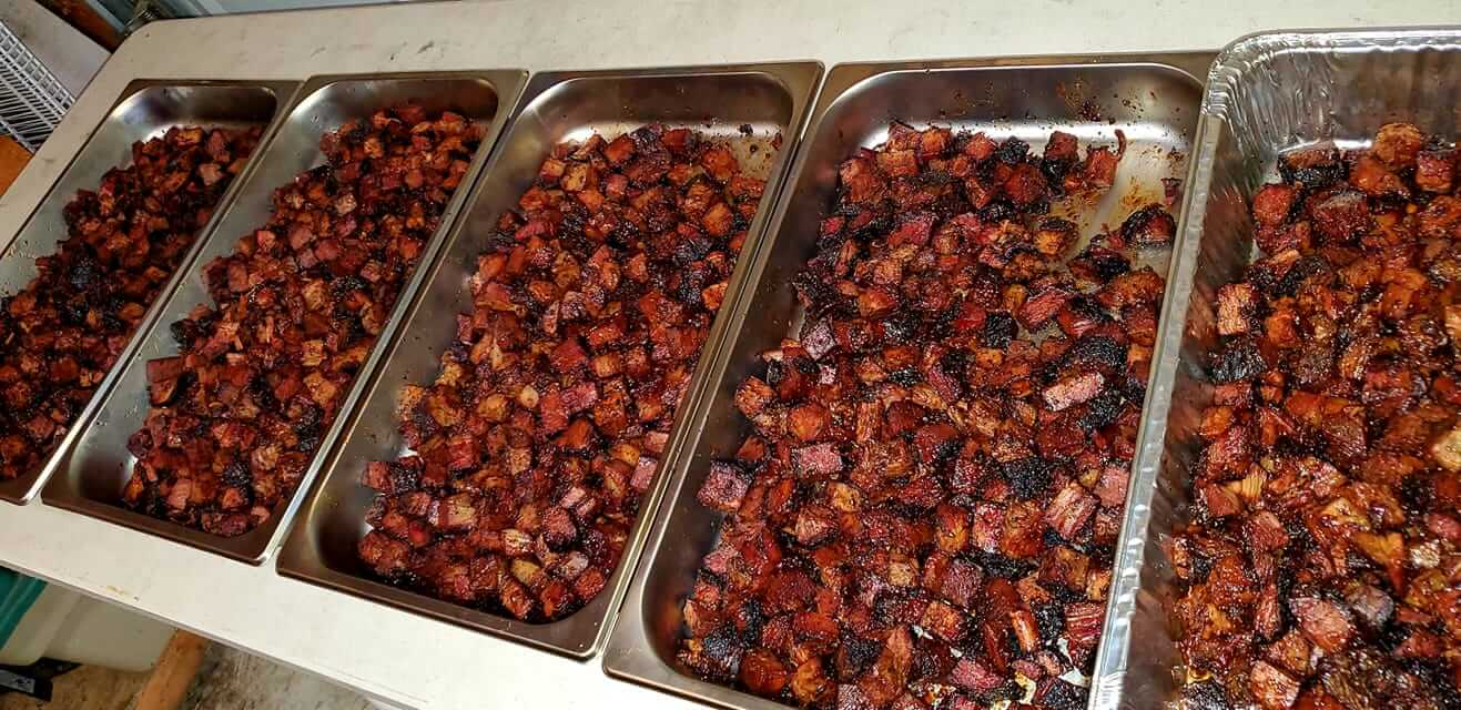 Four trays of food are lined up on a table