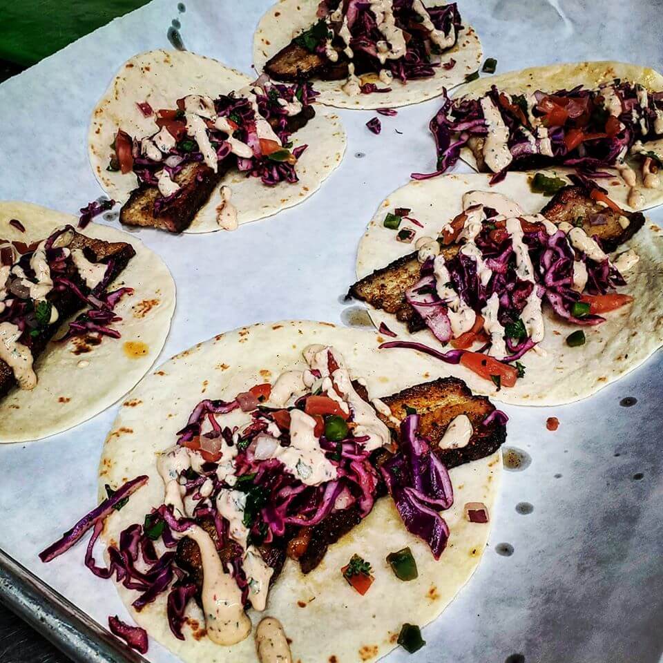 A bunch of tacos are sitting on a piece of wax paper