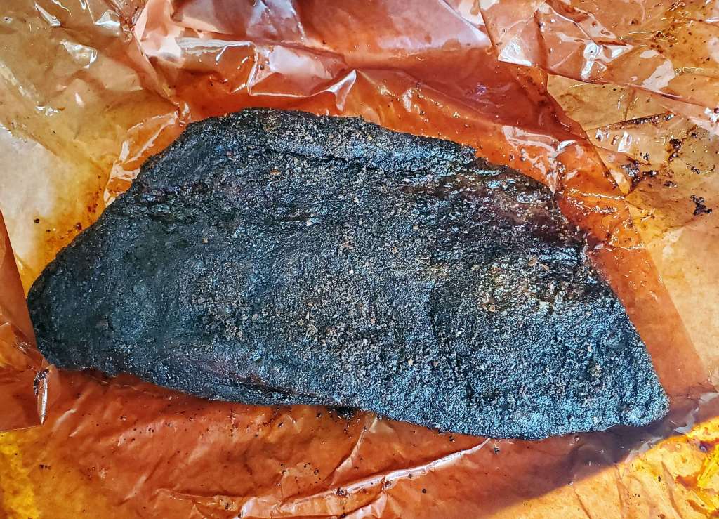 A piece of meat is sitting on a piece of wax paper