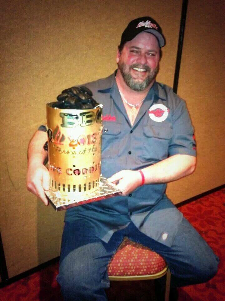 A man is holding a trophy with the year 2013 on it