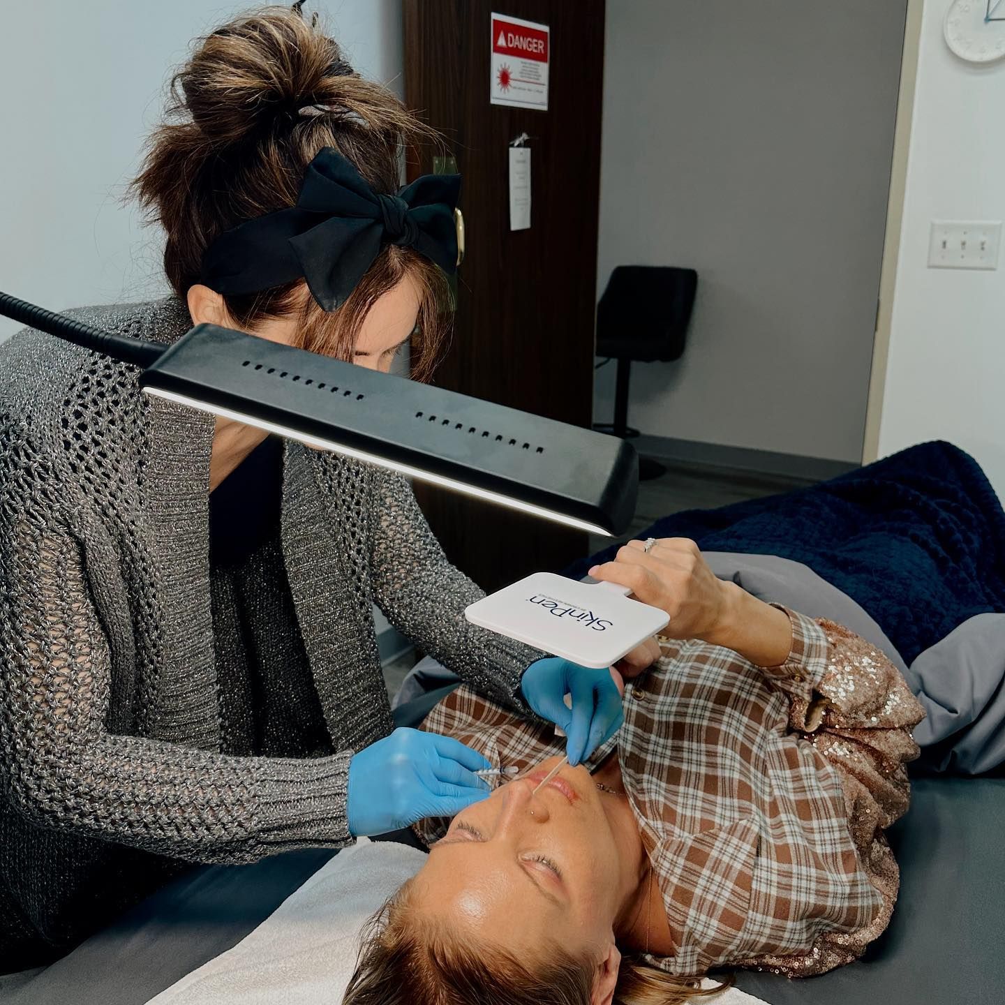 Dentist wearing a face shield examines a patient in a dental chair during treatment