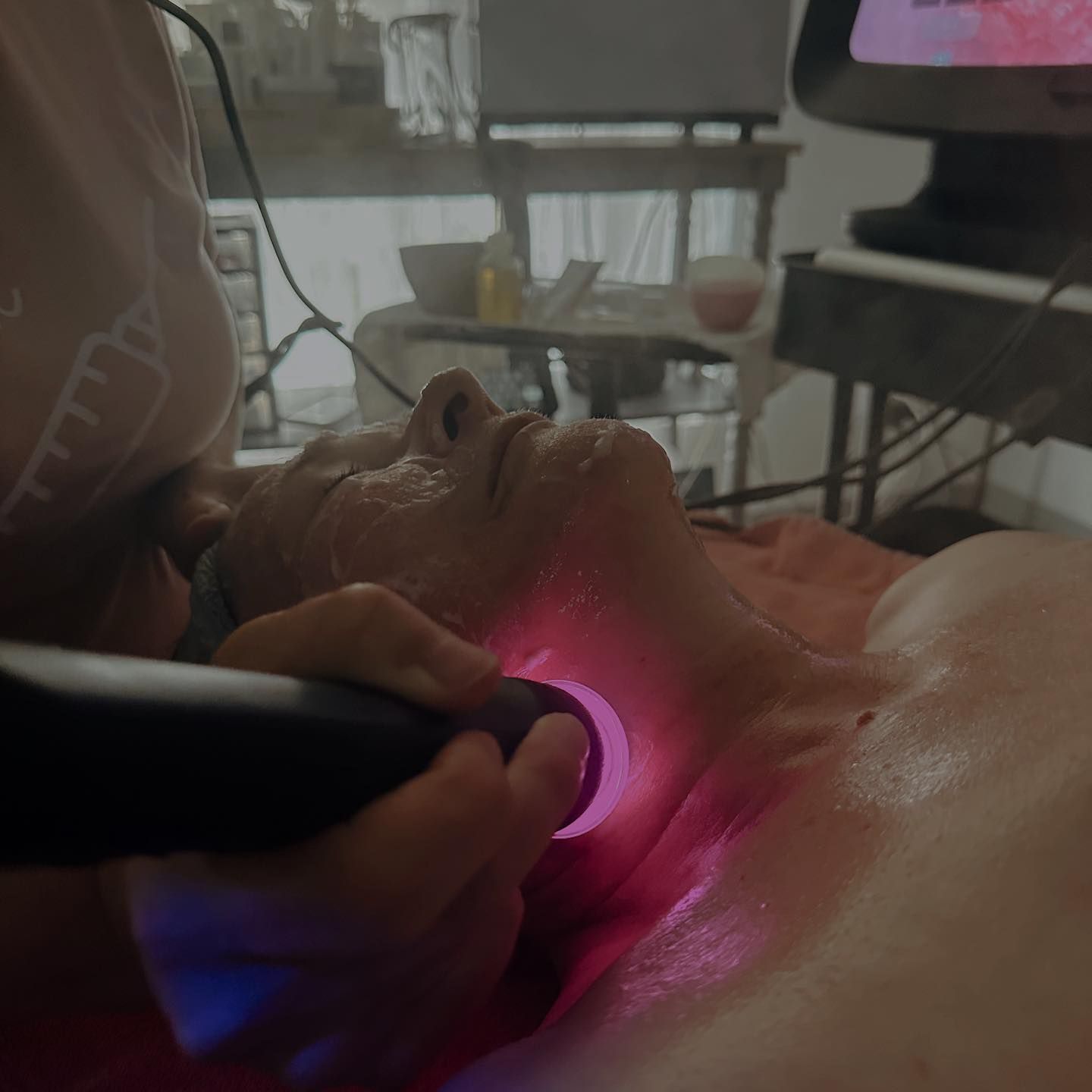 Person receiving a purple facial light treatment while lying down indoors