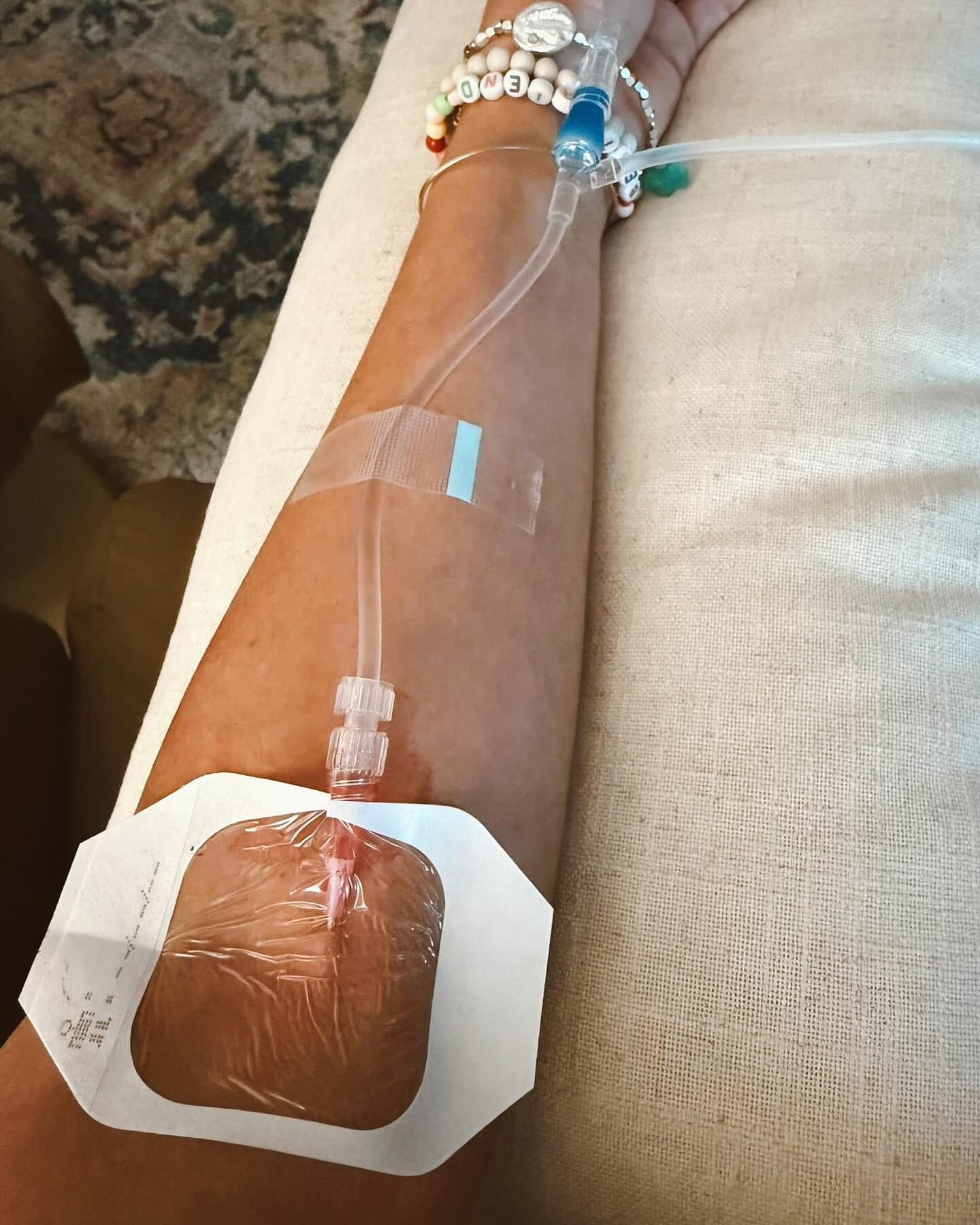 IV line taped to a patient’s arm with a clear catheter and gauze dressing