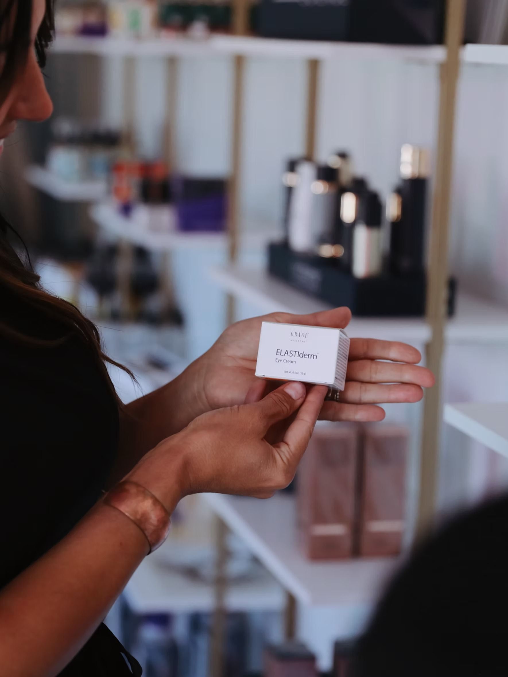 Person holding a small white product label in a blurred shop display area